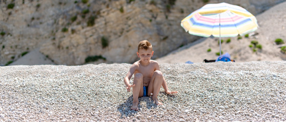 A boy is with pebbles on the beach