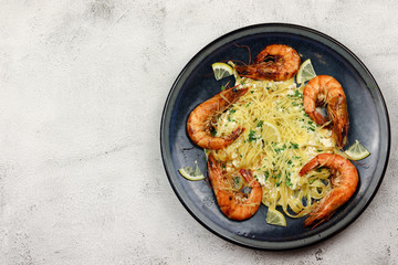 Fried prawns with tagliatelle in cream sauce in a plate on a light background. Top view, flat lay