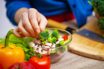 Concept of healthy eating, woman cuts fresh vegetables for salad