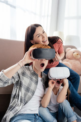 Shocked child using vr headsets with mothers in living room