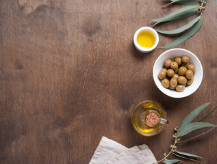 ripe natural eco friendly olives with olive oil in a bottle on a brown wooden background.