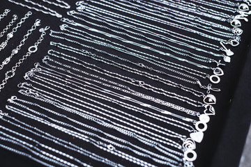 Bunch of silver necklaces with pendant on black cloth. Selective focus.