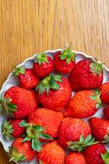 Fresh strawberries in white porcelain plate on wooden table