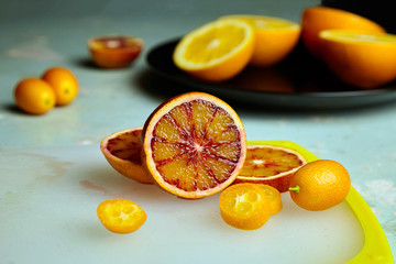 Blood or red orange and kumquat on cutting board, halves and slices of citrus fruits
