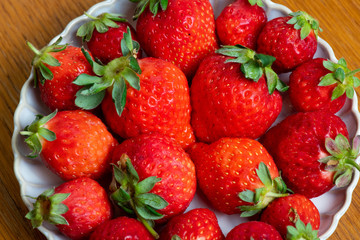 Fresh strawberries in white porcelain plate on wooden table