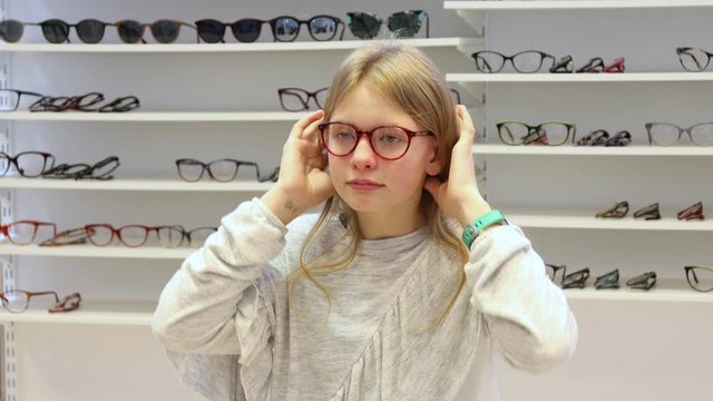 Young girl trying on new eyeglasses in an optics shop