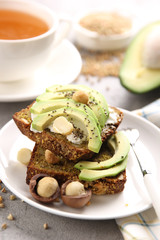 Healthy food. Breakfast with bread, avocado, nuts and cream cheese. White cup of tea and plate on a light background