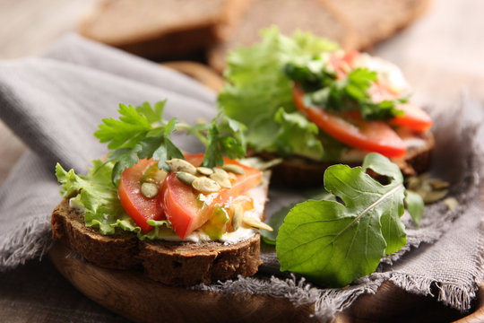 Healthy food. Bread with cream cheese, herbs, lettuce, tomatoes and pumpkin seeds on a grey wooden background. Rustic. Background image, copy space