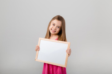 Naklejka premium baby girl in diapers holding a drawing Board on a blue background