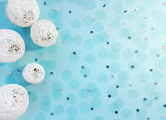 Composition of white balls from threads, sequins and tulle confetti on pastel blue background. Advertising content for the holiday. Flat lay, top view, copy space for your text