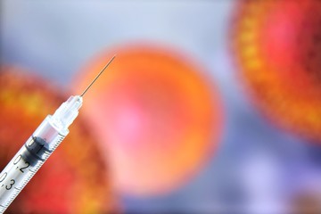 Syringe with a vaccine on blurred coronavirus bacteria’s on background. Stop epidemic. Coronavirus disease named COVID-19. Healthcare concept 