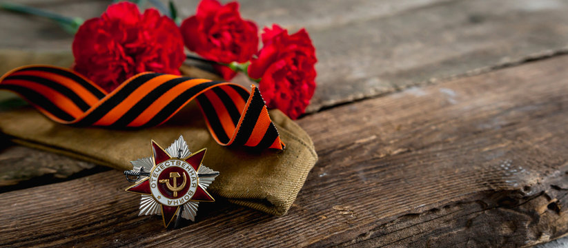 May 9, Victory Day holiday. Holiday card with order, St. George ribbon, flowers and military cap. May 9 background, copy space and translation with Victory Day.