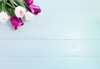 Composition of spring flowers on a light blue wooden background. White and purple tulips. Advertising content for Birthday, Valentines Day, Womens day. Flat lay, top view, close up, copy space