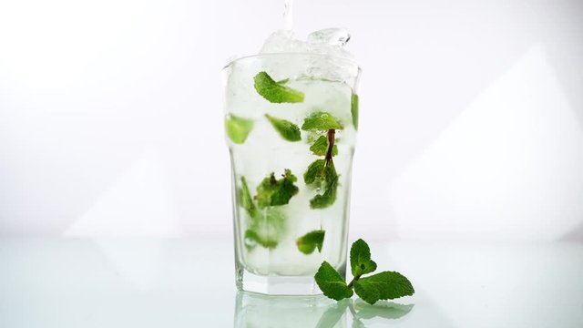 Pouring white Rum in a Mojito Cocktail on white Background