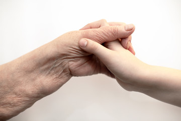 Human hands wrinkled adult senior and child holding each other. Bonding a great-grandmother and grandson. Love the emotion.