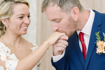 The groom with sincere love gently kisses the bride's hand.   A couple of newlyweds.