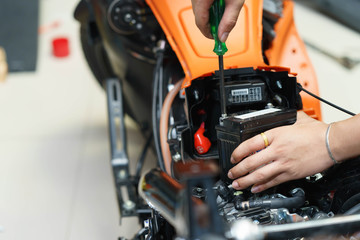 motorcycle mechanic replaces a battery. (maintenance)