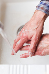 Wash hands with soap to prevent spread of germs Male hands washing in the sink
