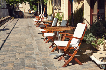 empty street cafe with wooden chairs and tables.