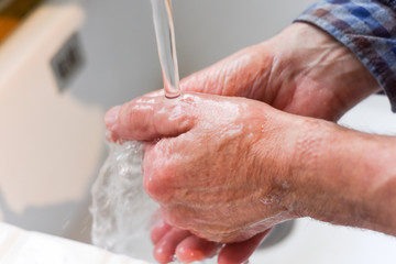 Wash hands with soap to prevent spread of germs Male hands washing in the sink
