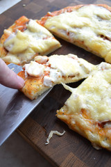 Tasty hot slice of pizza on a wooden board with melting cheese. Rustic pizza concept.