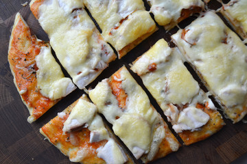 Tasty hot slice of pizza on a wooden board with melting cheese. Rustic pizza concept.