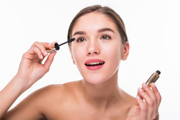Fototapeta premium Beautiful young woman with make up brush applying black mascara on eyelashes isolated on white background. Skin care theme