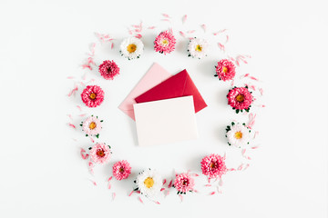 Beautiful flowers composition. Wreath made of pink and white flowers, pink envelopes on white background. Flat lay, top view, copy space