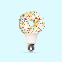 Lightbulb. White suggared donut like lamp on light blue background. Copyspace for your ad. Modern...