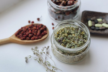  dried medicinal herbs, fruits and buds on a light background