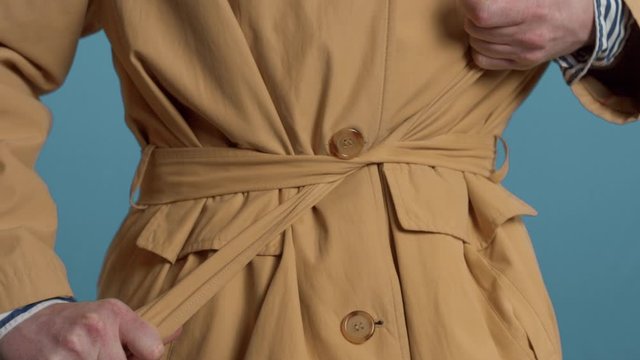 Closeup of mans hand tighten the belt of jacket. Colorful stylish look
