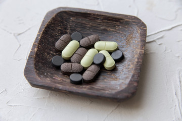  Natural dietary supplements in a square wooden bowl on the table