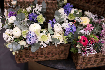 Bouquet of white ranunculus, red daisies, eucalyptus, blue hyacinths, white cherry in wicker willow box for sale