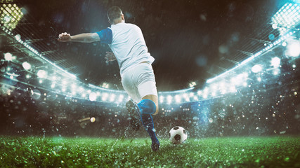 Close up of a soccer scene at night match with player in a white and blue uniform kicking the ball with power - obrazy, fototapety, plakaty