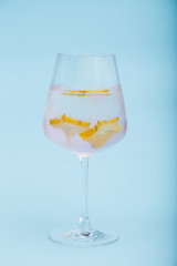 Glass of fresh iced cocktail decorated with starfruit slice on blue background.