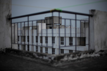 Blurred image of grills/railings of a rooftop/balcony in cloudy sky background.
