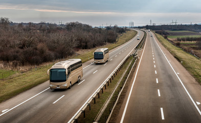 Two buses in line traveling on a highway country highway