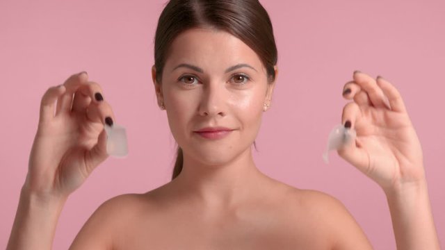 30s brunette woman takes off under eye patches and pass fingers on under eye zone