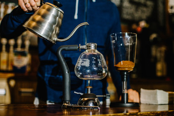 brewing coffee siphon. step by step cooking instructions. pouring siphon into the flask from the kettle of hot water