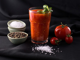 tomato juice in a glass on a black background.