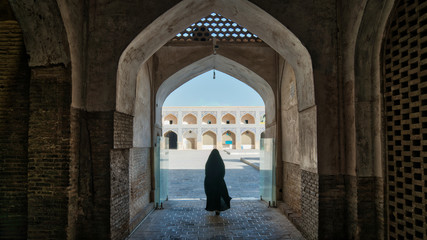 Unidentified woman in hijab walking towards the courtyard of the Great Mosque of Jameh Mosque of Isfahan, Iran