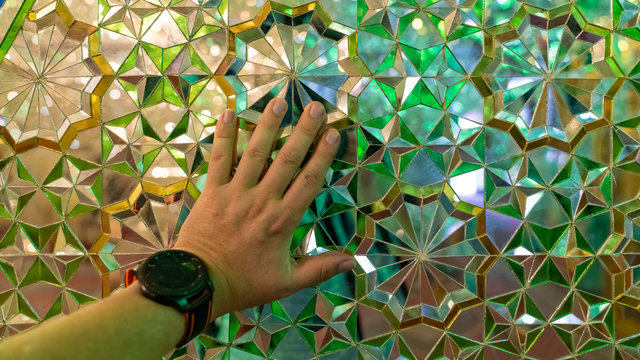 Hand touching the interior decoration of mirrors in Shah e Cheragh Shrine, Shiraz, Iran