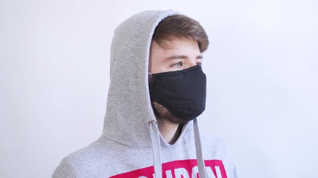 A young man putting on a black mask for Corona Virus protection.