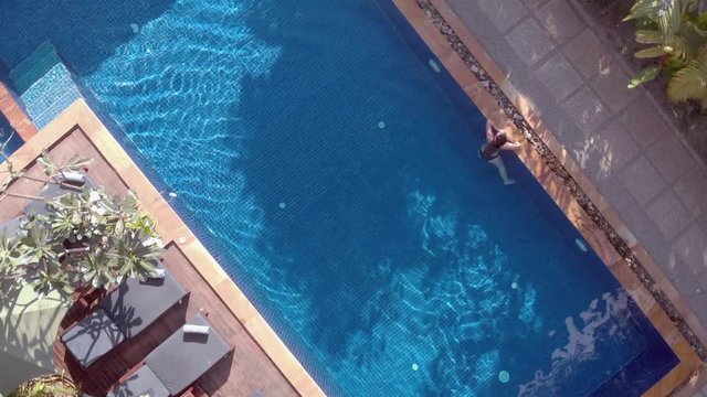 Slow Drone Shot Ascending and Rotating Above a Tropical Hotel Swimming Pool