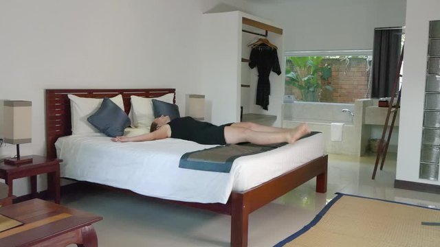 Wide Slow Motion Shot of a Young Woman Jumping on a Hotel Bed