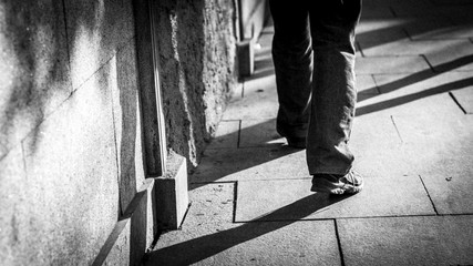 piernas de hombre con sombras caminando por la calle en blanco y negro 