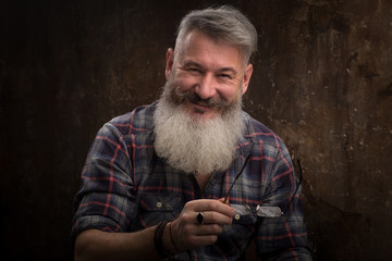 Studio portrait of a gray-haired middle-aged bearded man smiles at the camera, selective focus
