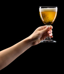 Woman hand holding lager beer glass isolated on black.