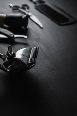 On a black dusty surface are old barber tools. Vintage manual hair clipper comb razor shaving brush...