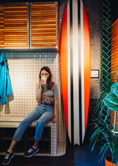 Informal girl with drink cup in surf coffee house